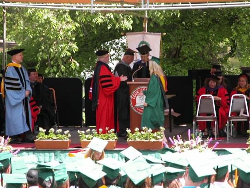 A graduate recieving a diplima on a stage.