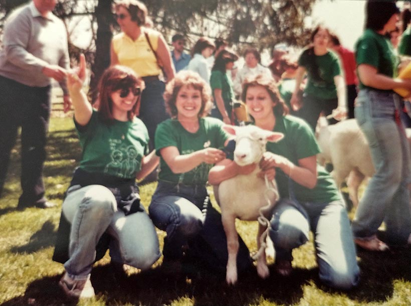 Three students holding a sheep.