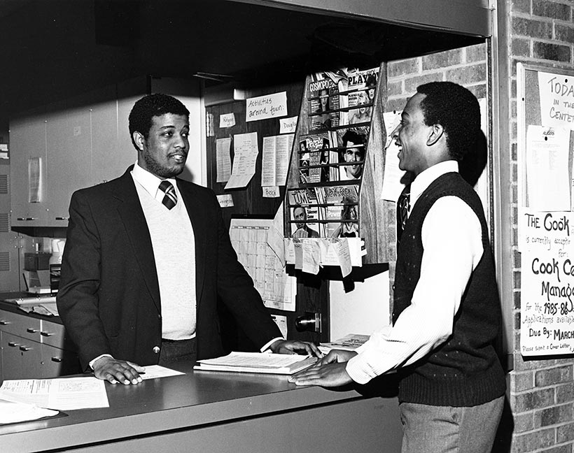 A student speaking to a clerk at an information desk.