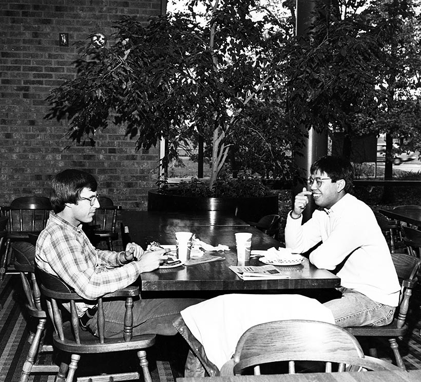 Two students sitting at a table eating.