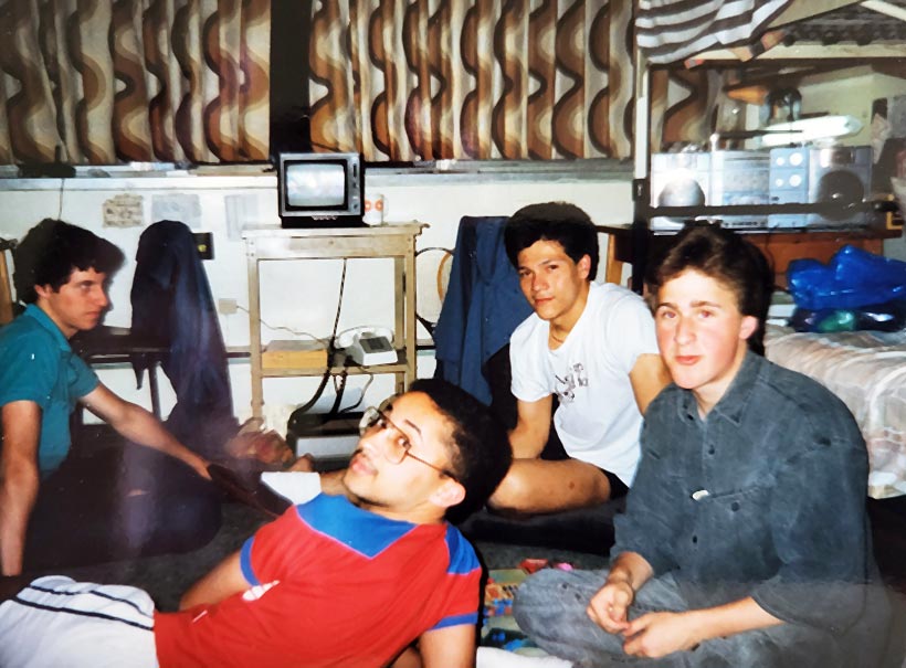 Four students sitting on the floor of a dorm room.